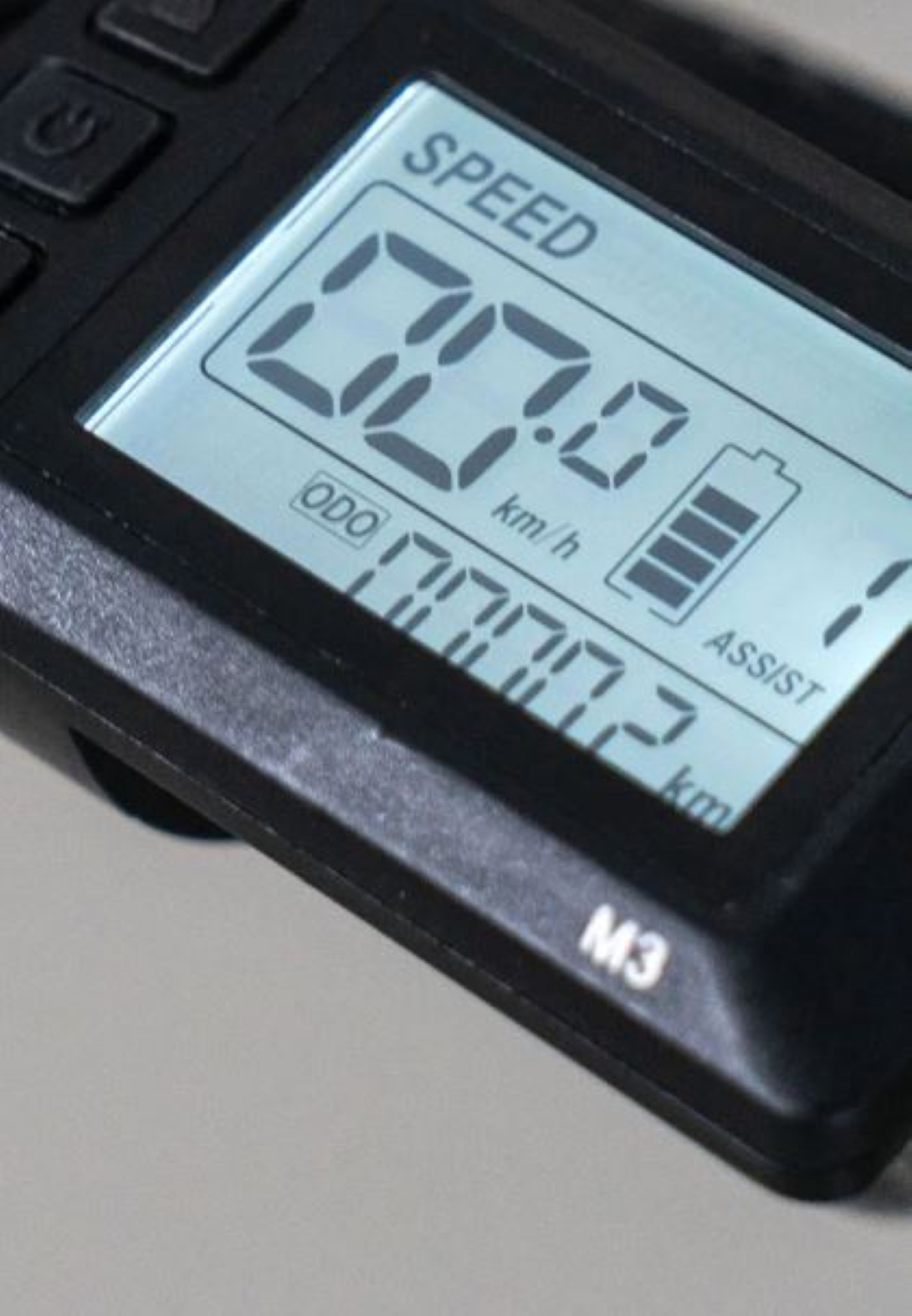 Primo piano del display della bici che mostra velocità e livelli della batteria. Il display è nero.