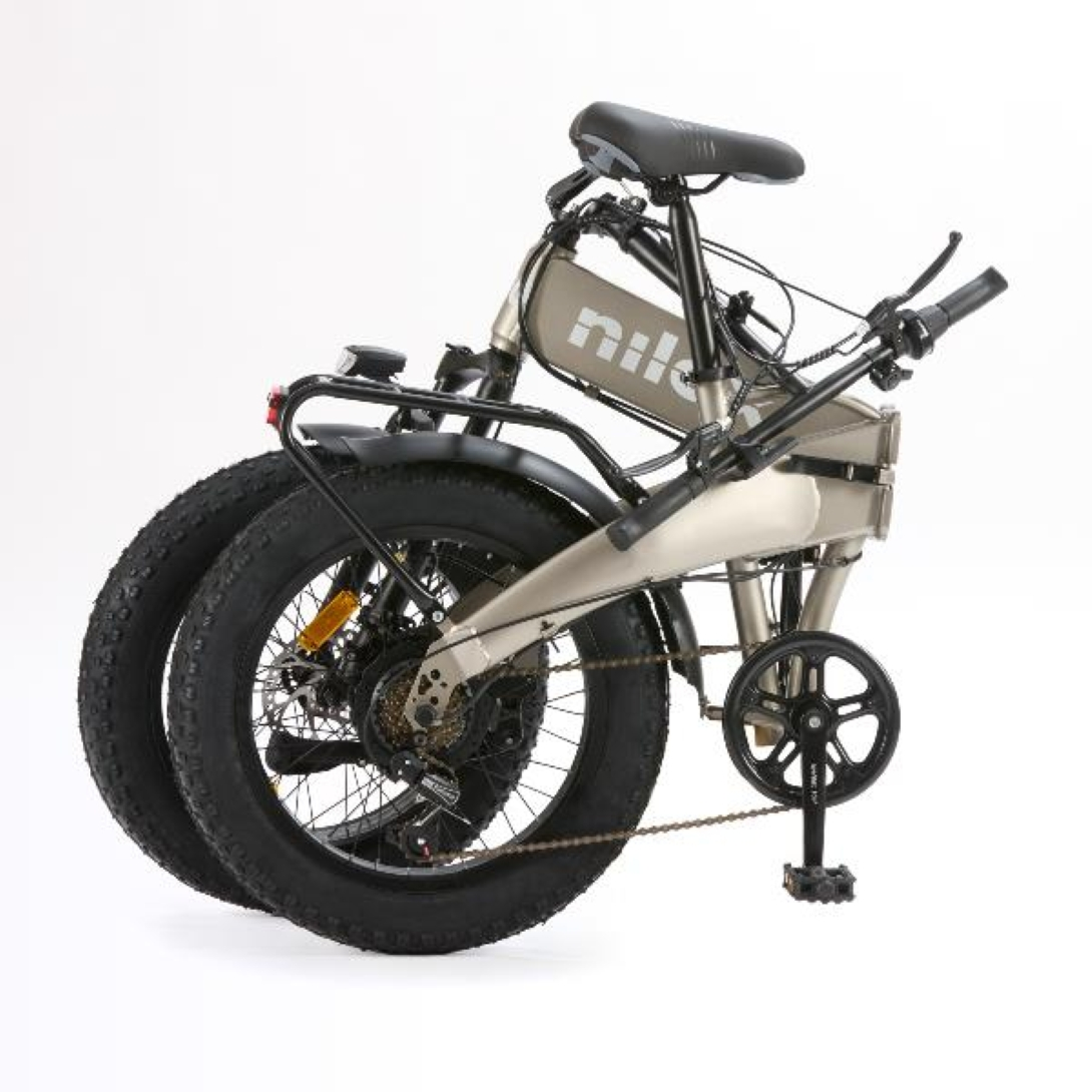 Złożony srebrny rower na białym tle. Widoczne czarne opony, koła zębate i pedały.