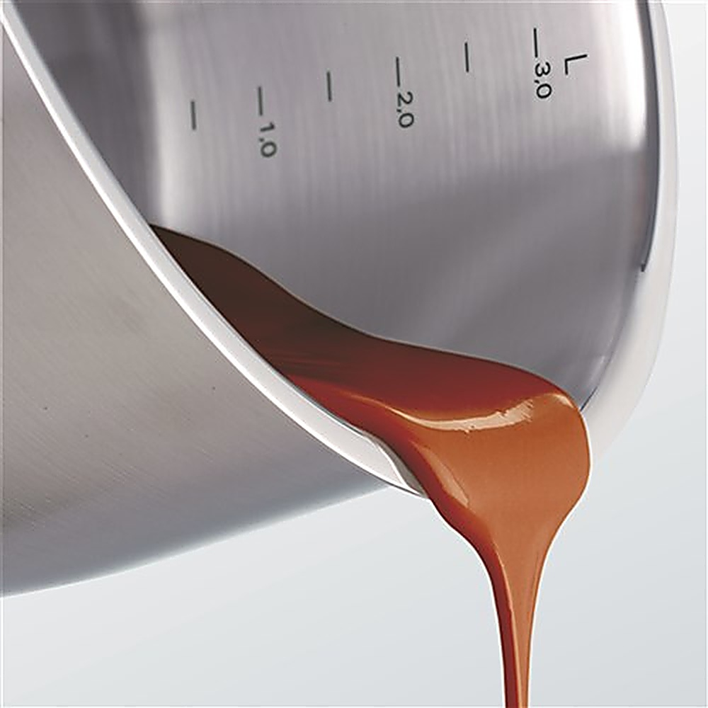 Srebrny garnek wylewający brązowy płyn. Widoczne oznaczenia objętości. Białe tło.