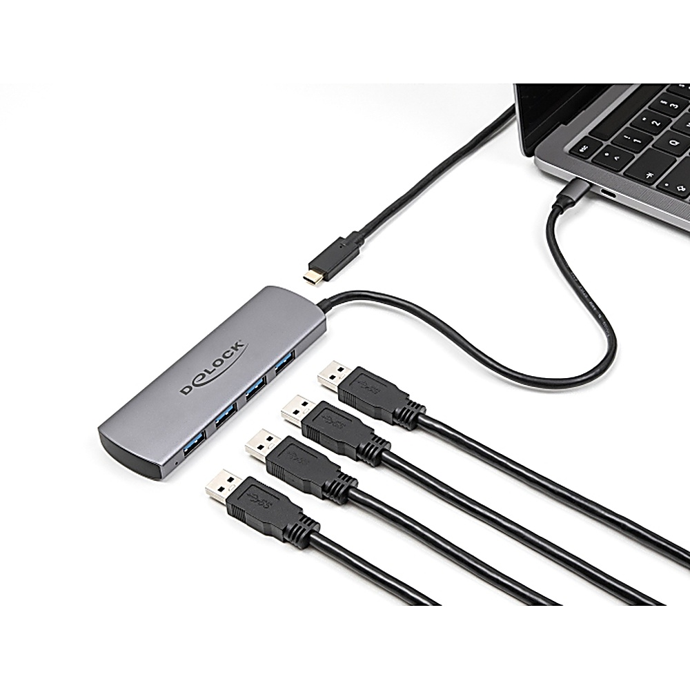 Un hub USB argentato con porte USB e diversi cavi USB neri collegati ad esso e a un laptop.