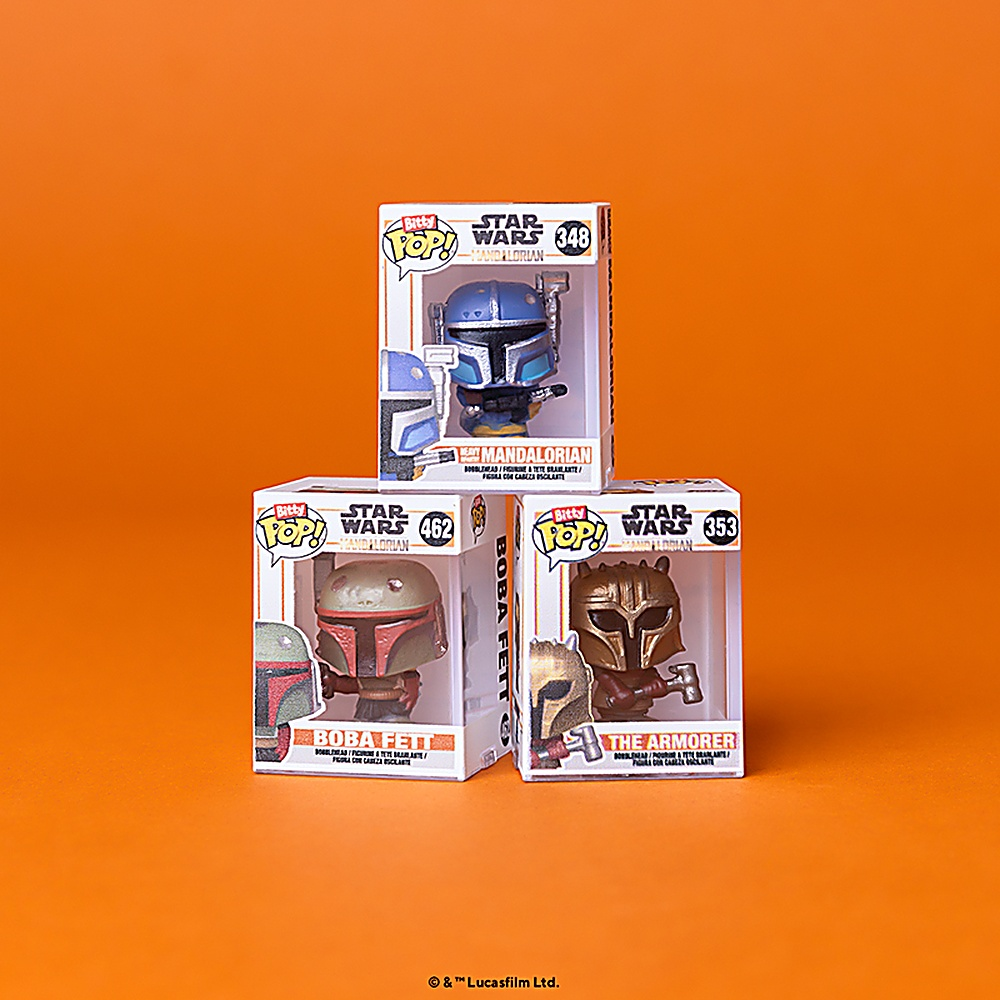 Trzy pudełka Funko Pop z Gwiezdnych Wojen: The Mandalorian, Boba Fett i The Armorer na pomarańczowym tle.