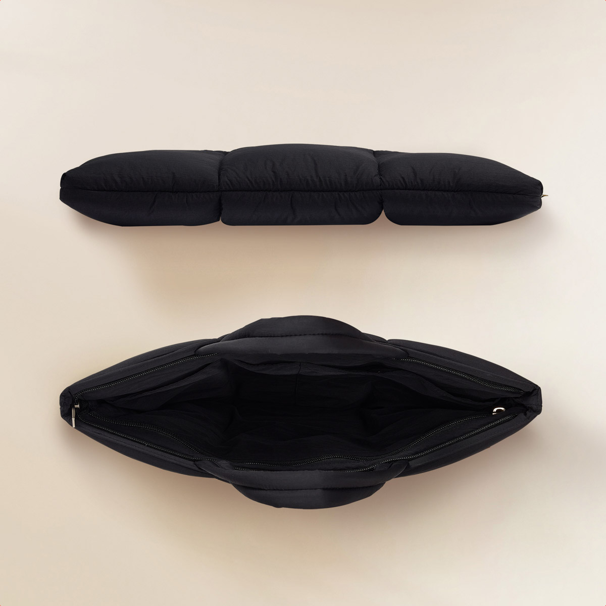 Two black quilted bags, one open, one closed. Both on a light background. Features zipper and stitching details.