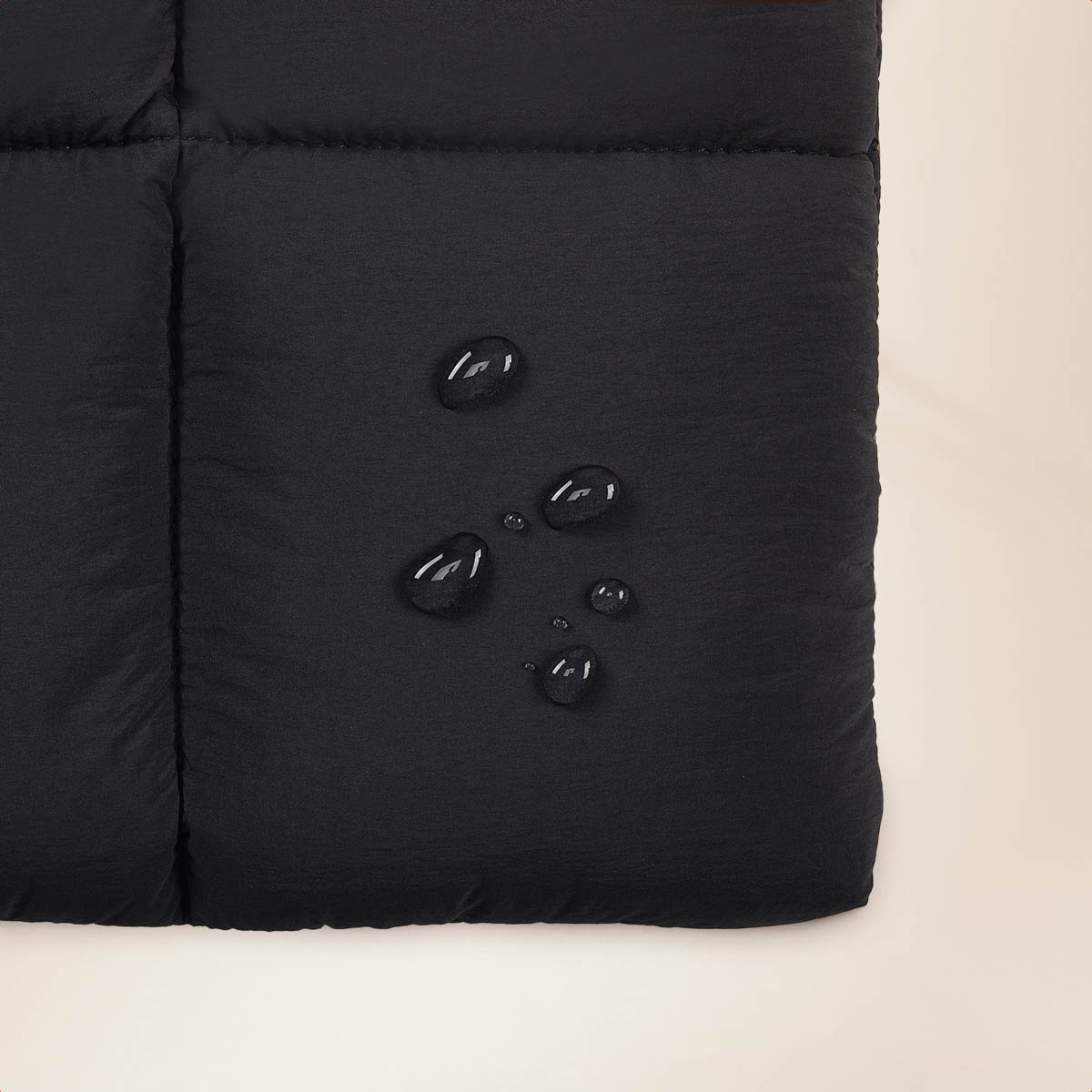 Close-up of water droplets on black fabric, showing water resistance of the material.