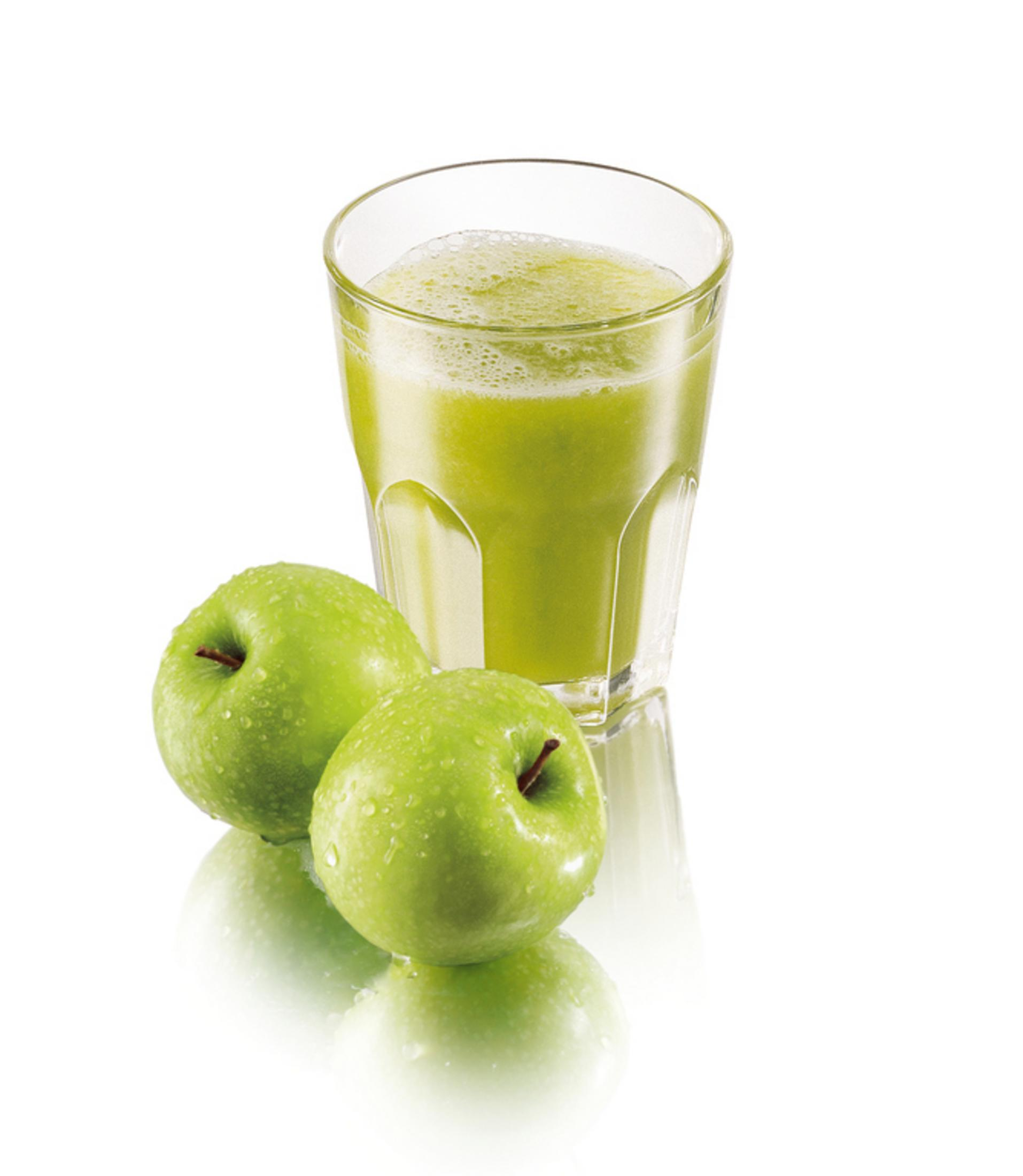 Ein Glas grüner Saft mit zwei grünen Äpfeln daneben. Die Äpfel und das Glas spiegeln sich auf einer weißen Oberfläche.