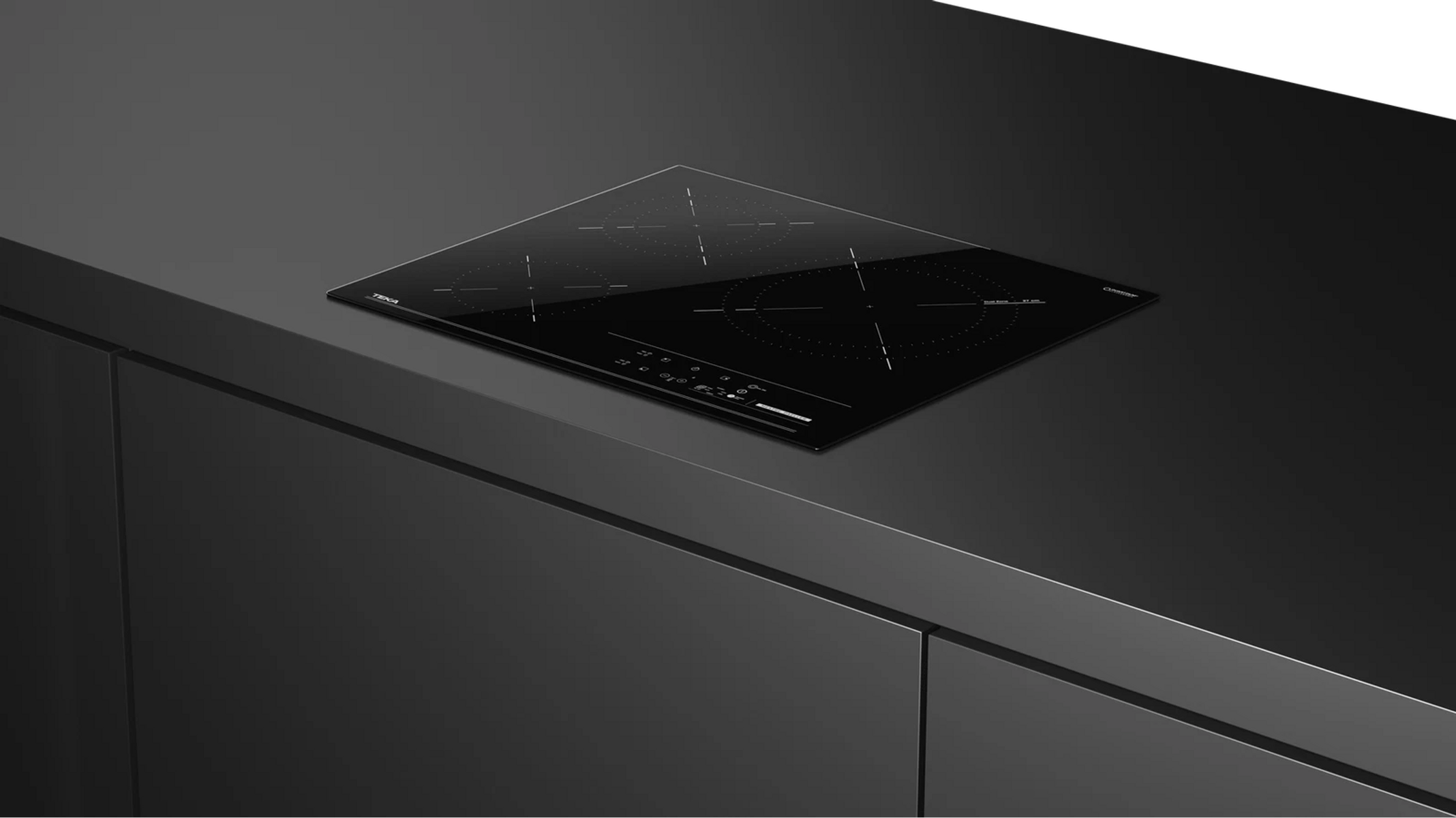 Un elegante piano cottura a induzione nero su un piano di lavoro scuro, con quattro fuochi e comandi touch.