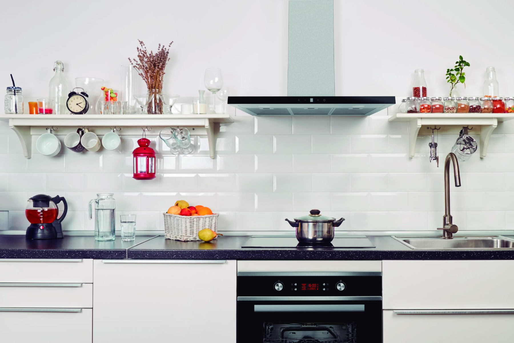 Cocina con gabinetes blancos, estantes con decoración, placa de cocina negra y horno.