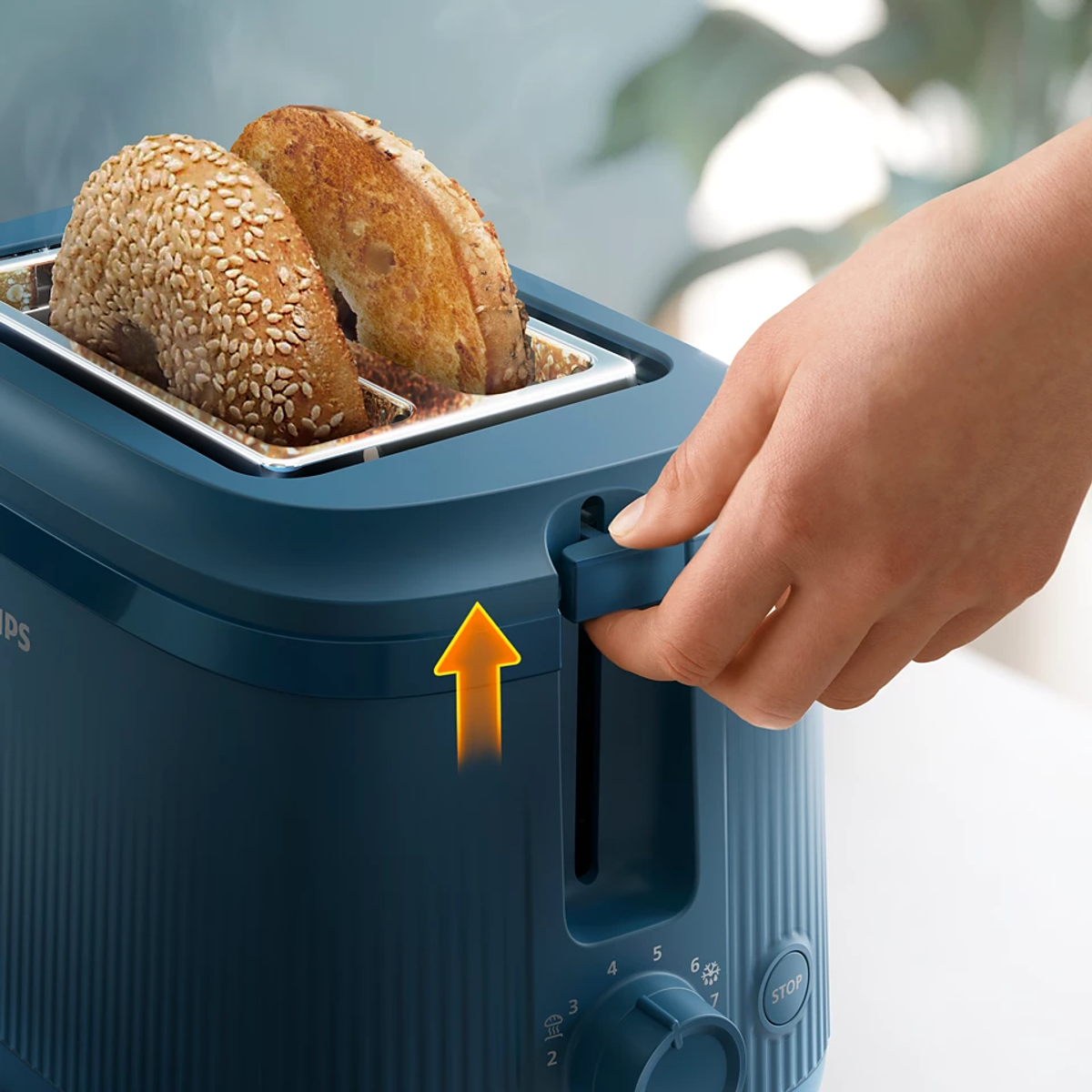 Toster z dwoma kromkami chleba w środku. Ręka pociąga za dźwignię.