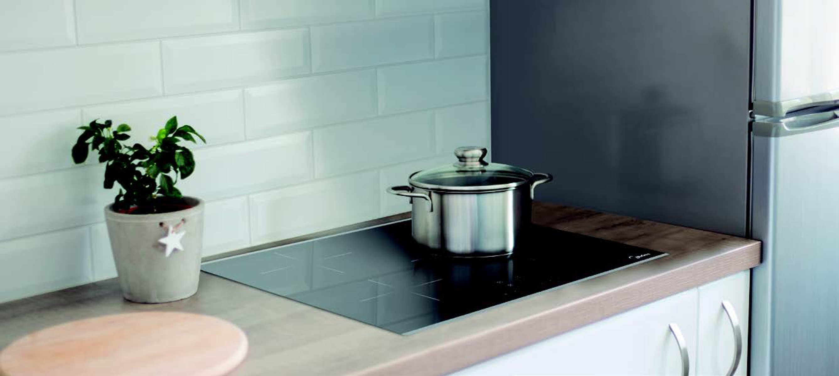 Una cocina moderna con armarios blancos y una vitrocerámica negra.