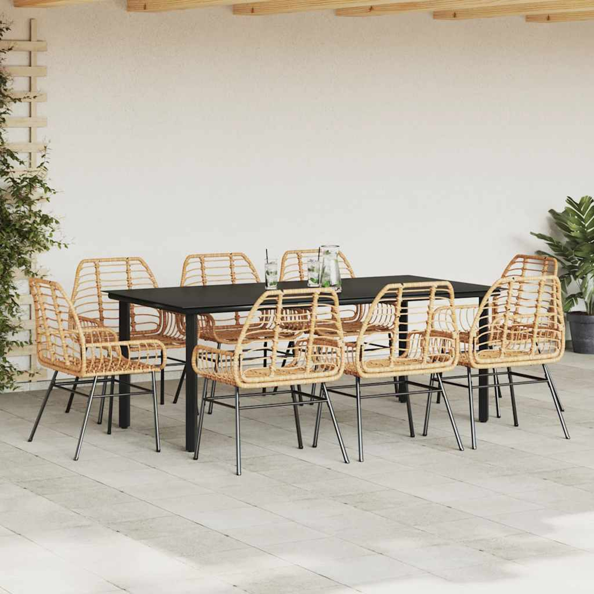 Essgruppe im Freien mit schwarzem Tisch und Rattanstühlen, vor einer weißen Wand und Terrasse.