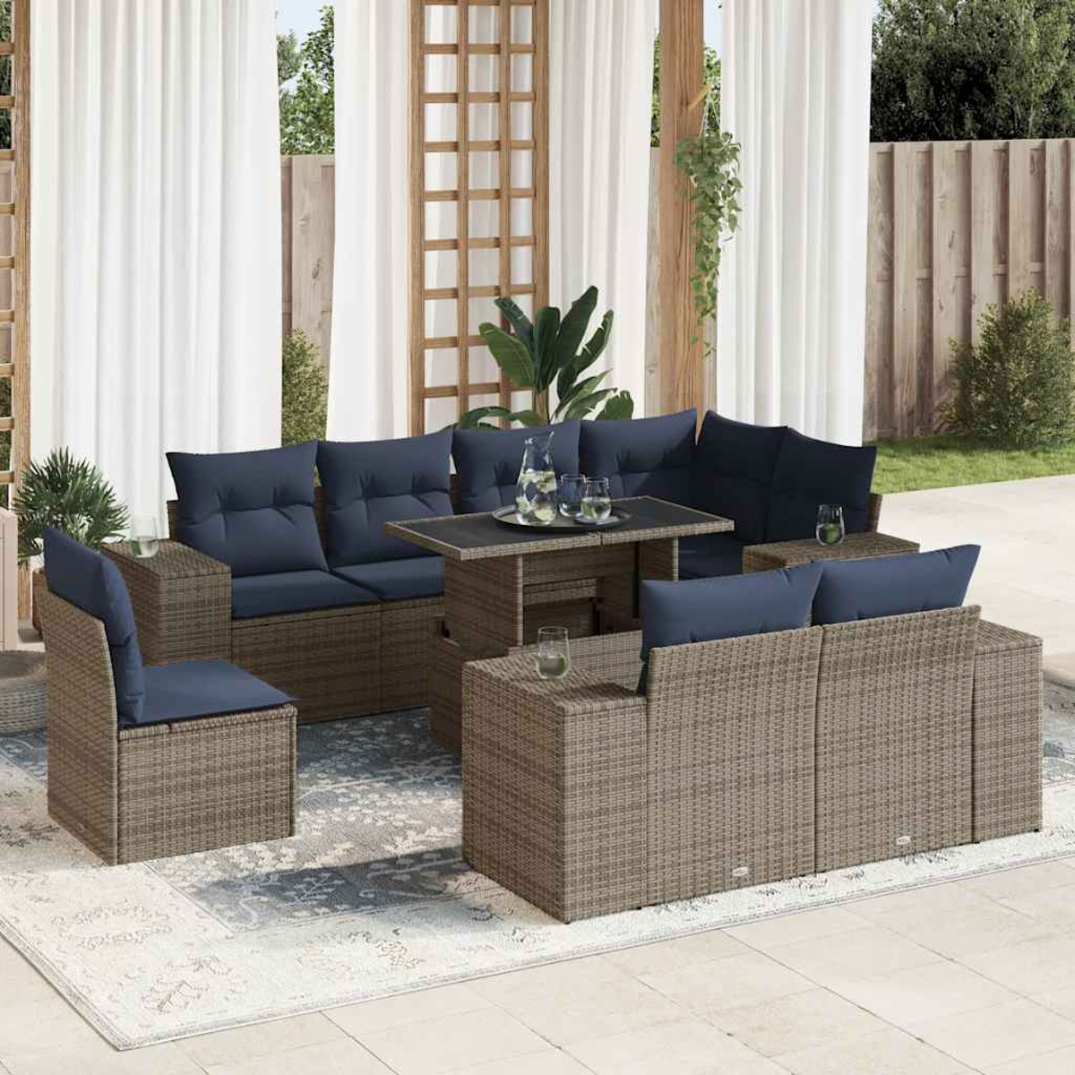 Rattan-Ecksofa mit blauen Kissen und einem Tisch. Die Szene spielt in einem Garten. Graue Farbe.