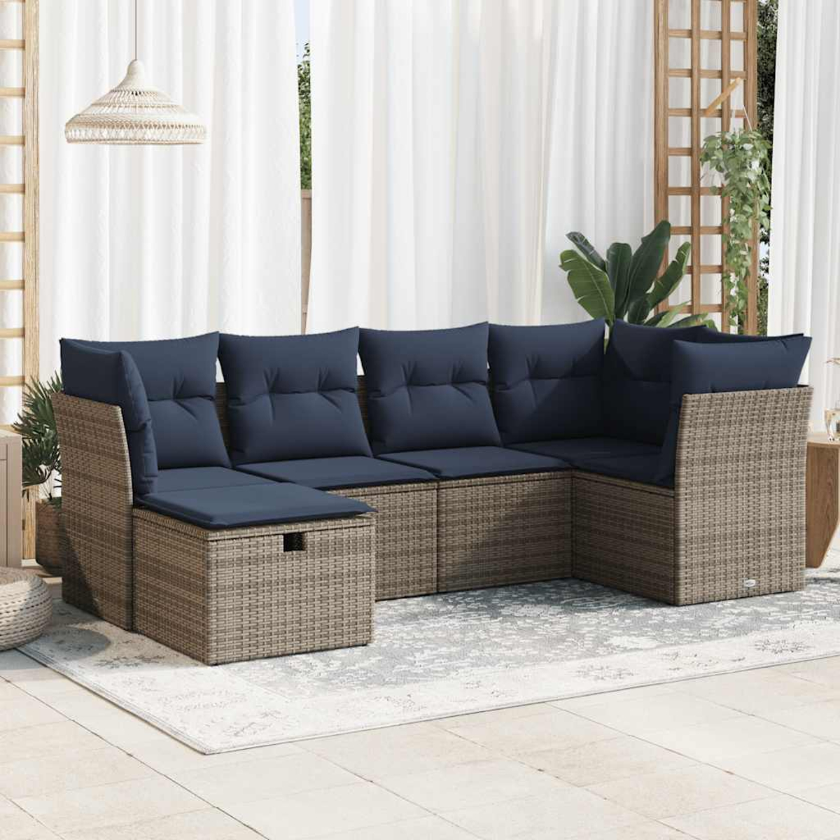 Geflochtenes Ecksofa für draußen mit blauen Kissen. Auf Terrasse mit Vorhängen und Pflanzen.
