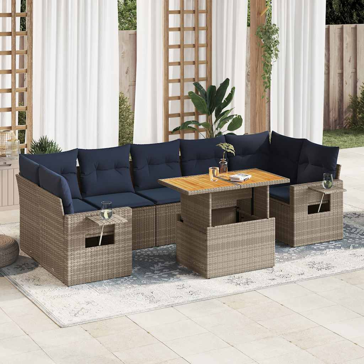 Outdoor-Ecksofa mit marineblauen Kissen und einem Holztisch auf einem gemusterten Teppich vor weißen Vorhängen.