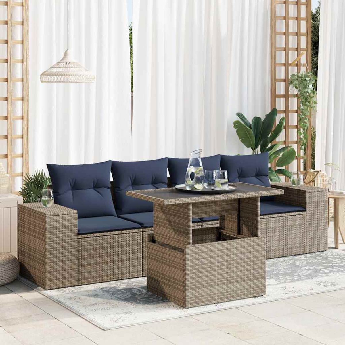 Outdoor-Rattan-Sofagarnitur mit Tisch und Gläsern. Weiße Vorhänge im Hintergrund.