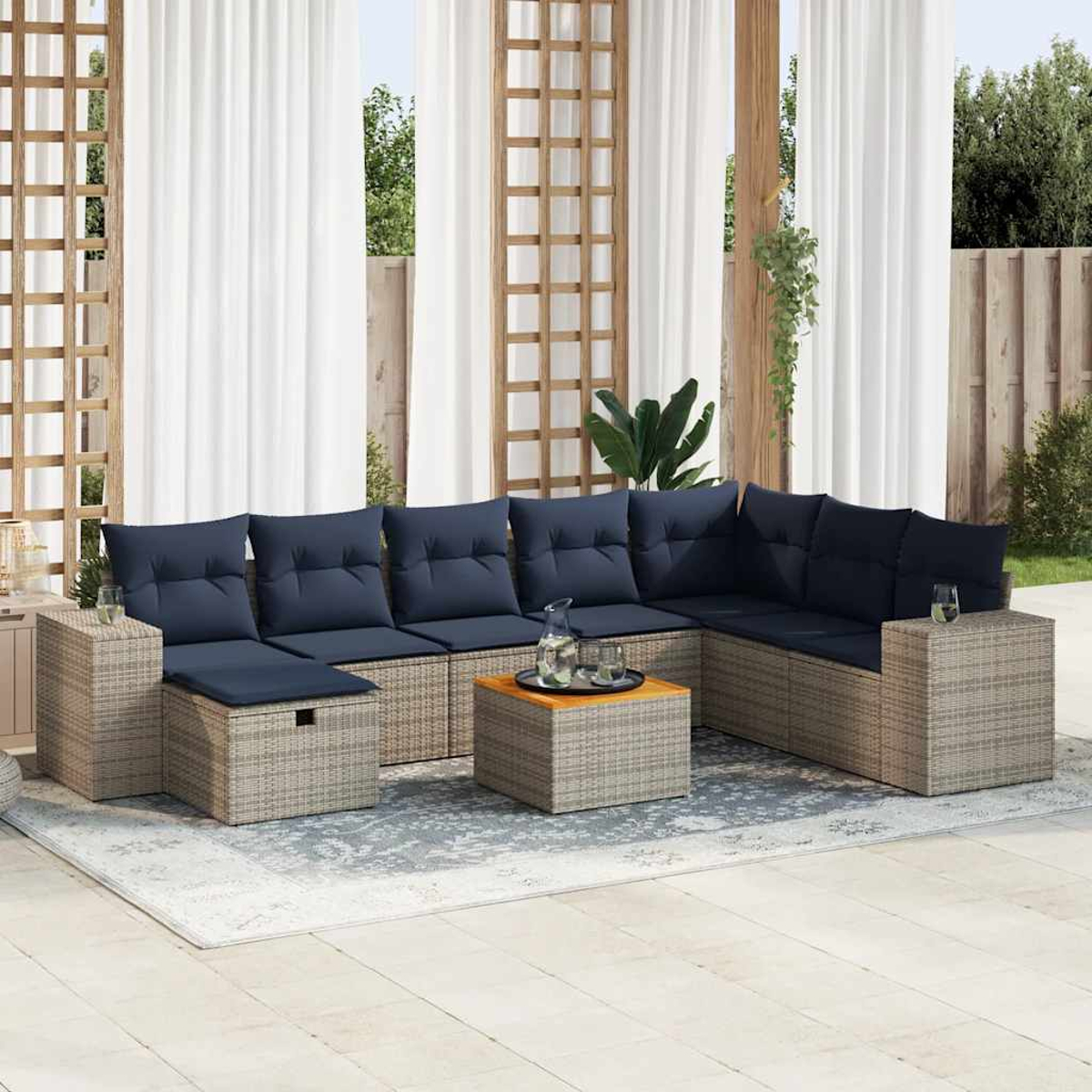 Rattan-Sofagarnitur mit Tisch und Gläsern auf einem Teppich. Weiße Terrasse.