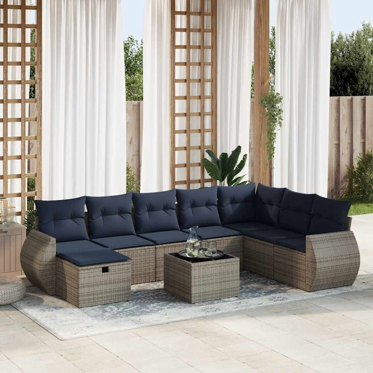 Outdoor-Ecksofa mit marineblauen Kissen und einem Holztisch auf einem gemusterten Teppich vor weißen Vorhängen.