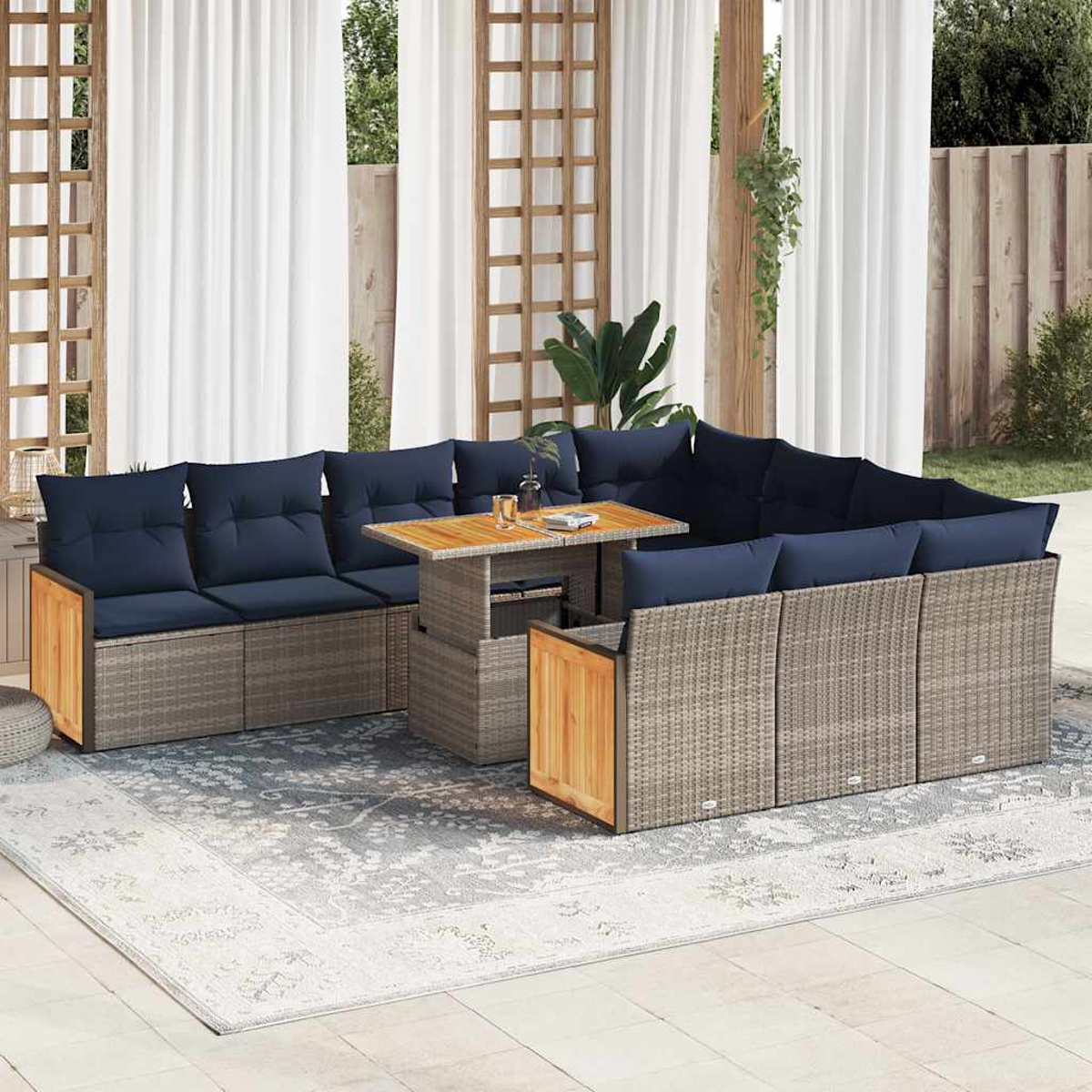 Ein Sitzbereich im Freien mit einem hellfarbigen Ecksofa aus Korbgeflecht, blauen Kissen und einem Tisch.