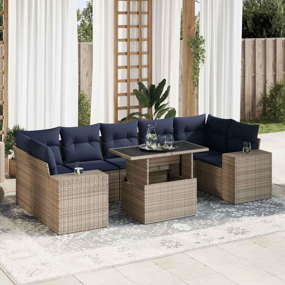 Ein graues Rattan-Ecksofa mit blauen Kissen und einem Tisch mit Hubplatte, auf einem gemusterten Teppich.