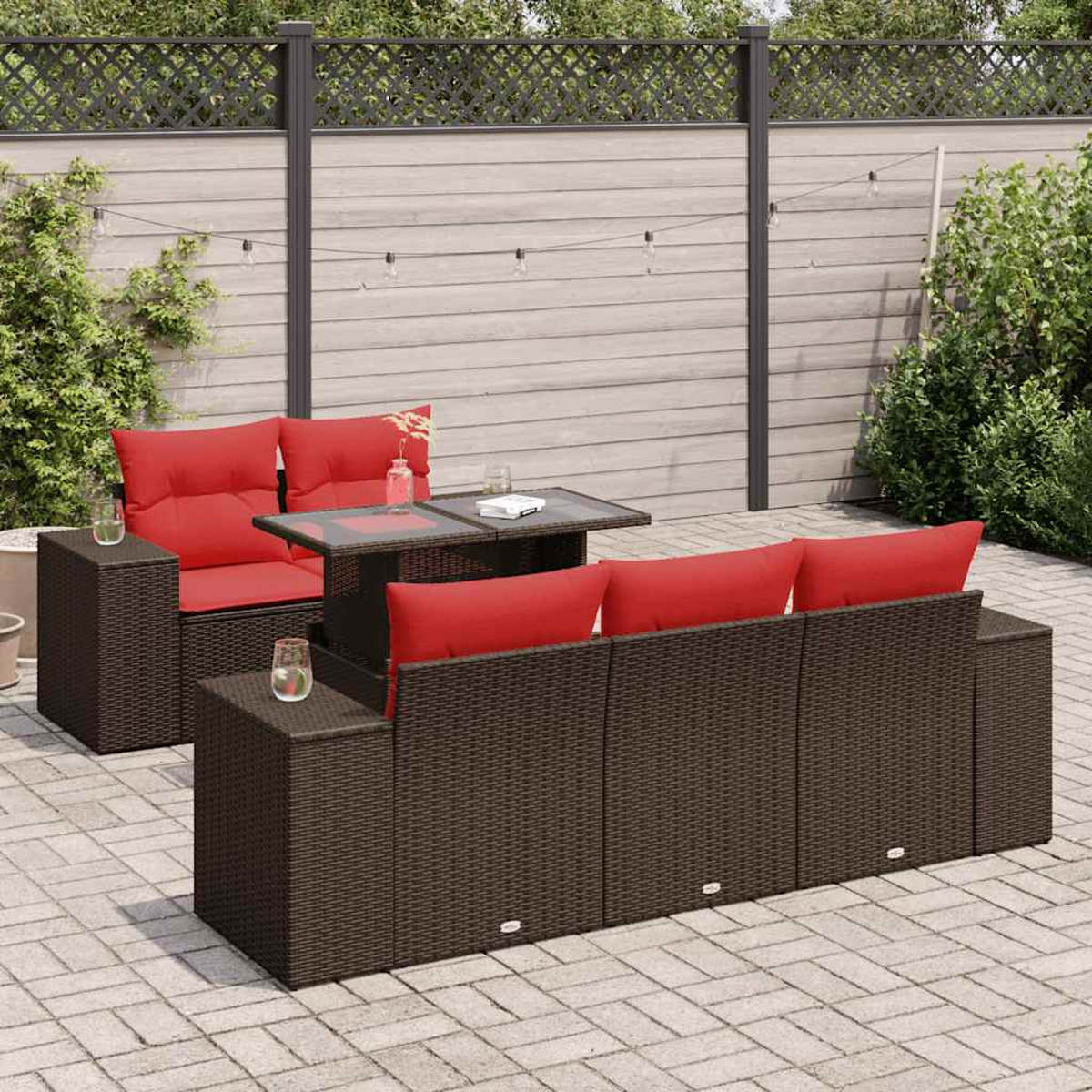 Outdoor-Set mit braunem Korbmöbel, roten Kissen, Tisch und Gläsern.