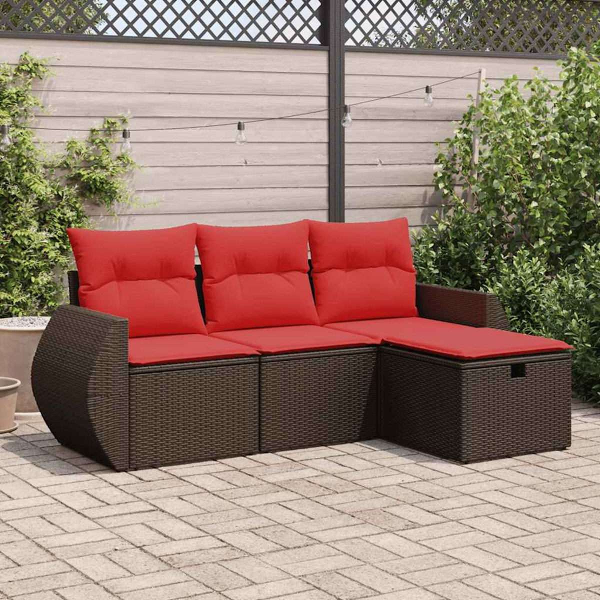 Ein dunkelbraunes Korbmöbelsofa mit roten Kissen und einer Chaiselongue auf einer Ziegelterrasse.