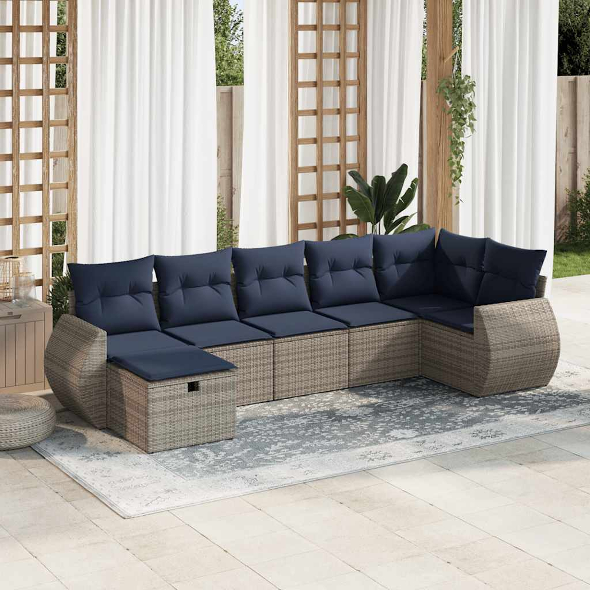 L-förmiges Outdoor-Sofa mit blauen Kissen, Rattangestell und hellem Teppich auf einer Terrasse.