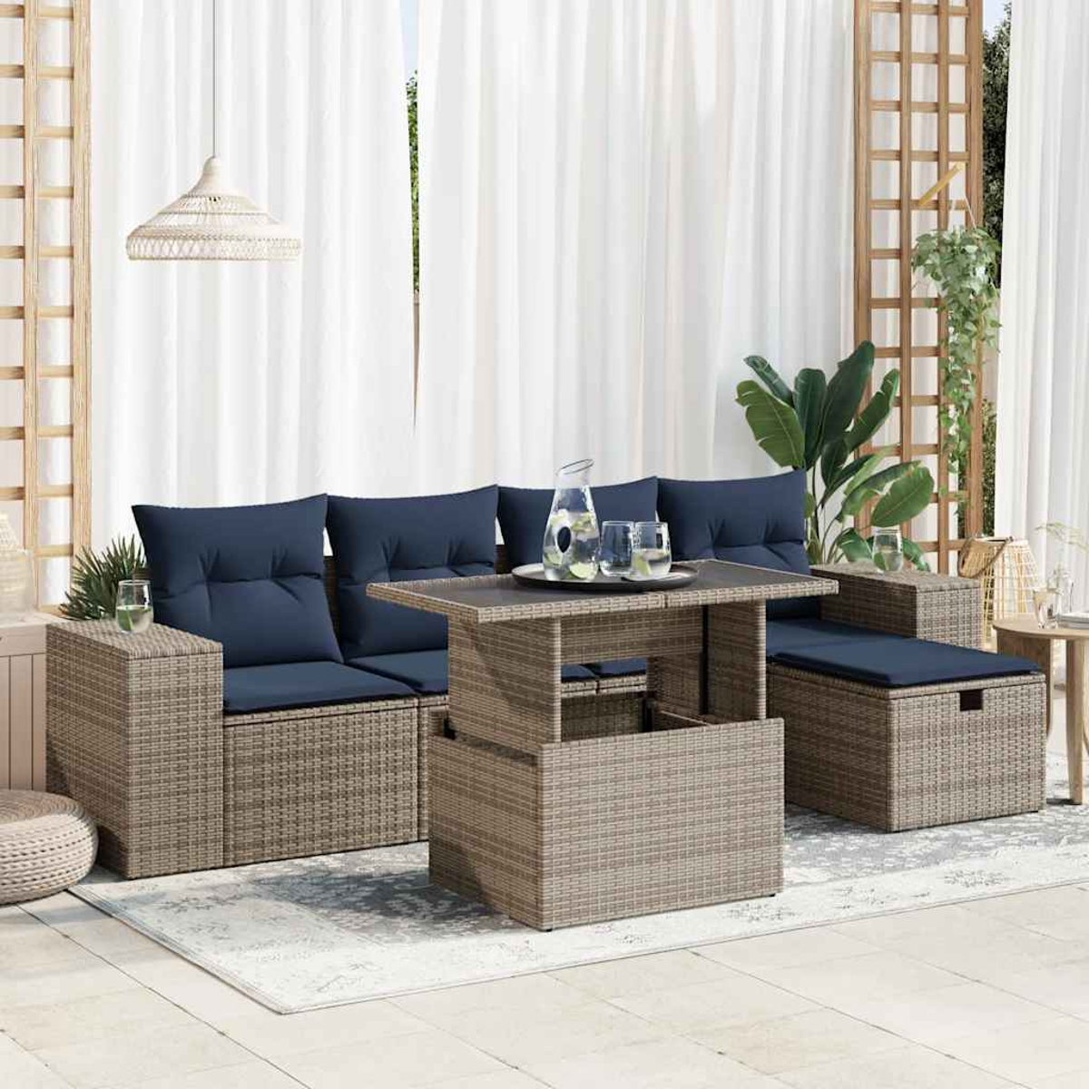Ein Rattan-Sofaset mit blauen Kissen, einem Couchtisch und Pflanzen in der Nähe eines weißen Vorhangs.