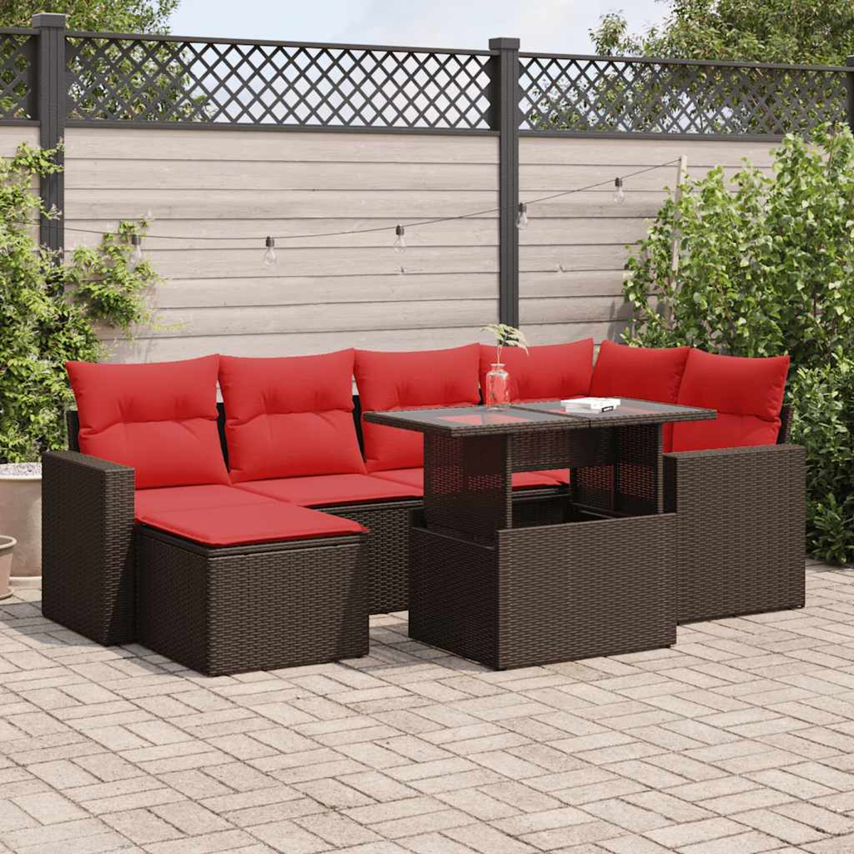 Outdoor-Ecksofa mit roten Kissen und einem Tisch mit Glasplatte. Braune Korbmöbel auf einer Terrasse.