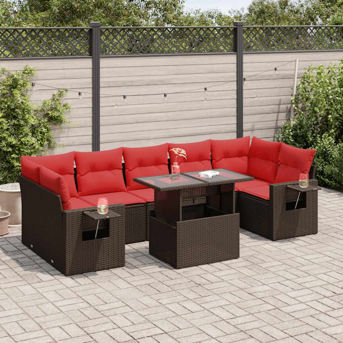 Outdoor-Ecksofa mit roten Kissen und einem Tisch mit Glasplatte. Braune Korbmöbel auf einer Terrasse.