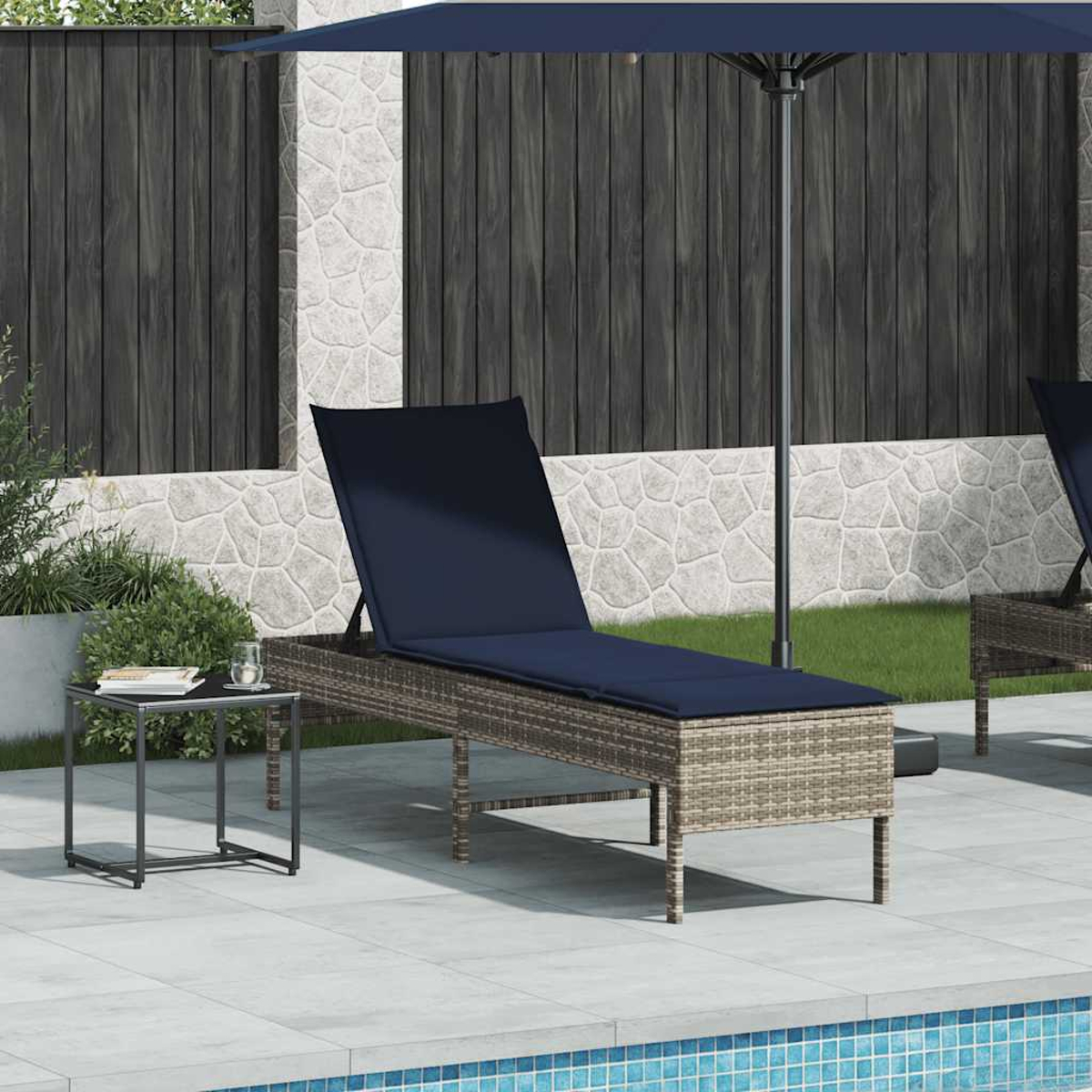Outdoor-Liegestuhl mit grauem Weidenrahmen und marineblauem Kissen. Daneben steht ein kleiner schwarzer quadratischer Tisch.