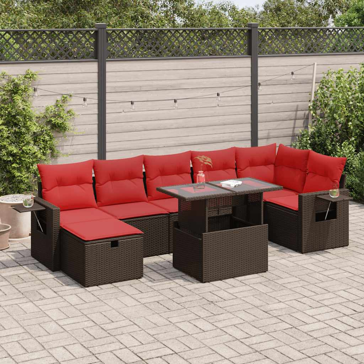 Braunes Outdoor-Wicker-Set mit roten Kissen und einem Tisch mit Glasplatte. Backstein-Terrasse.