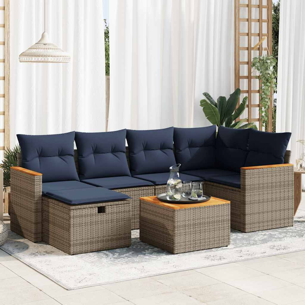 Rattansofa-Set mit blauen Kissen und einem hölzernen Beistelltisch. Es liegt auf einem Teppich.