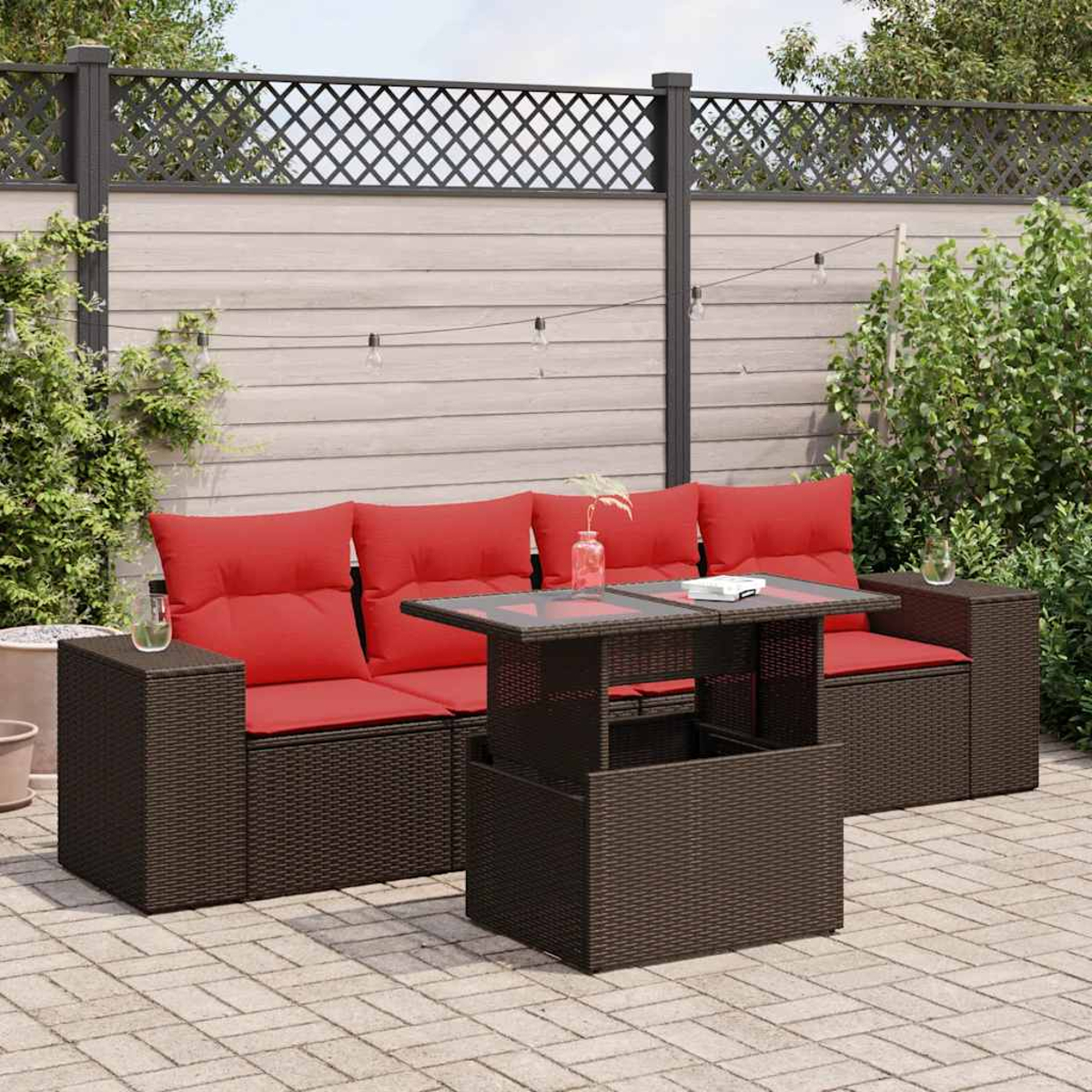 Braune Rattan-Gartenmöbel mit roten Kissen und einem Tisch mit Hubplatte auf einer Terrasse.