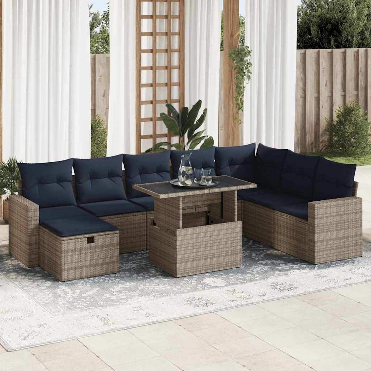 Rattan-Möbelset mit blauen Kissen und einem Tisch mit Hubplatte auf einem gemusterten Teppich.