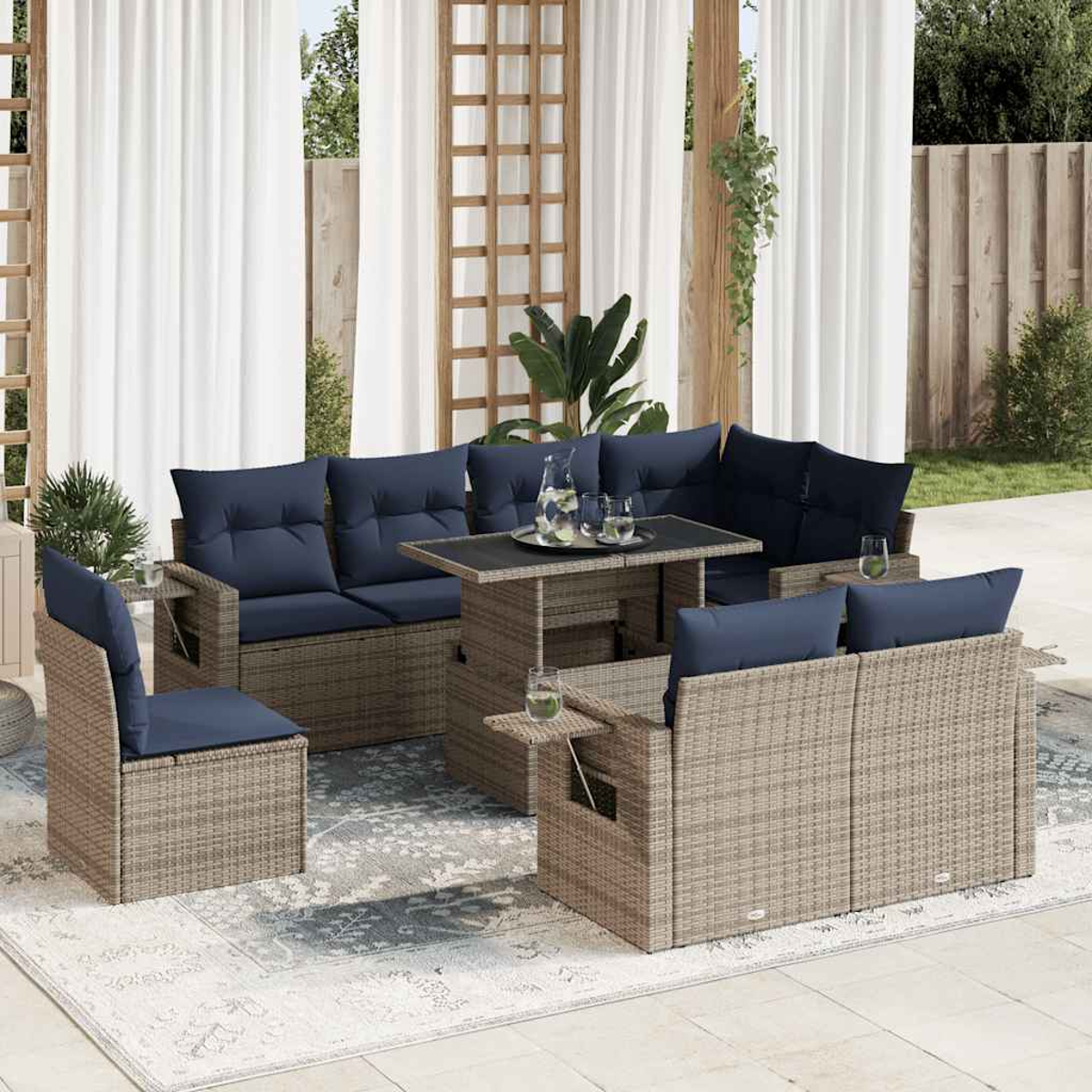 Graues Outdoor-Sitz-Set aus Korbgeflecht mit blauen Kissen und Hubtisch auf einem Teppich.