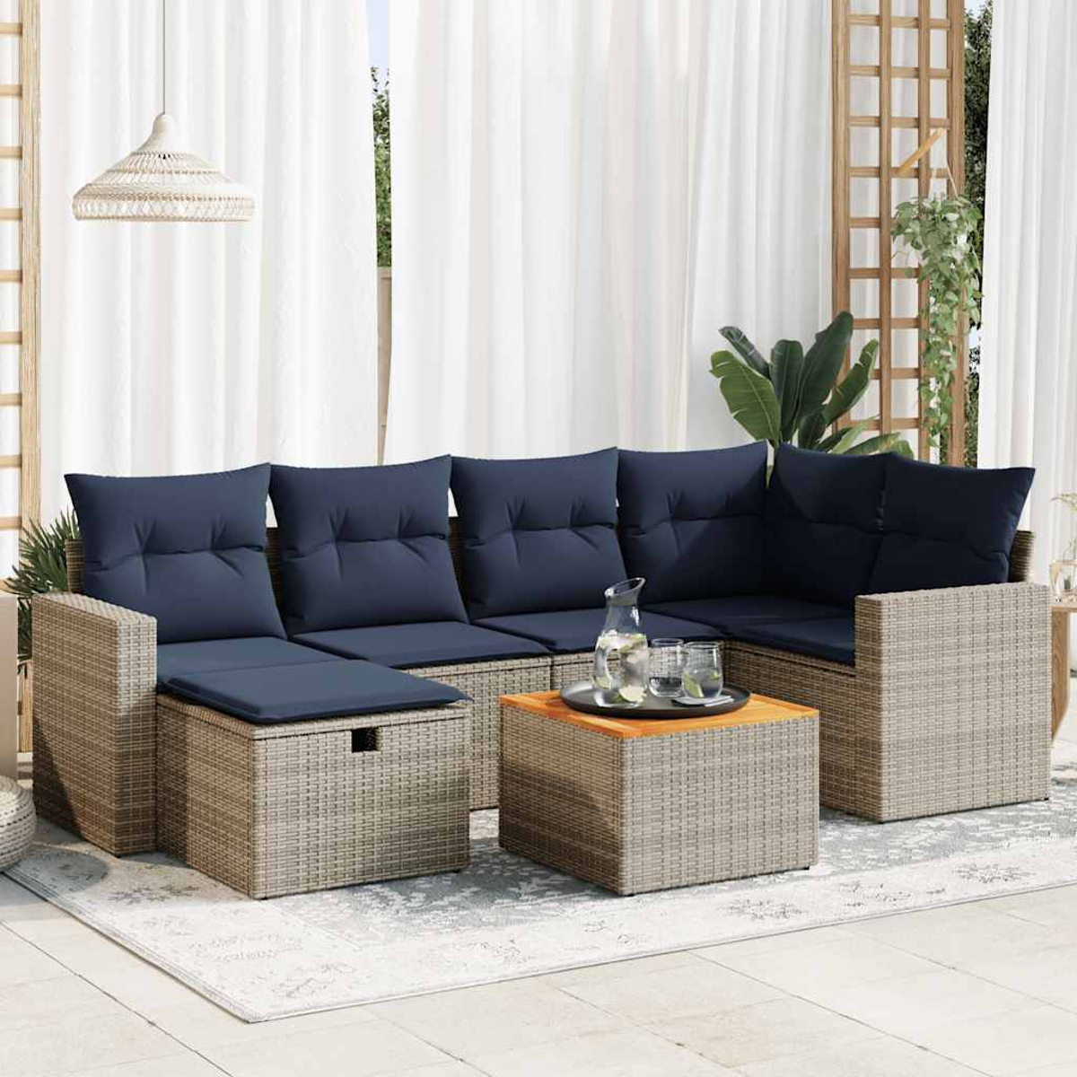Ein Ecksofa im Freien mit blauen Kissen und einem kleinen Tisch auf einem Teppich. Vorhänge und Pflanzen im Hintergrund.
