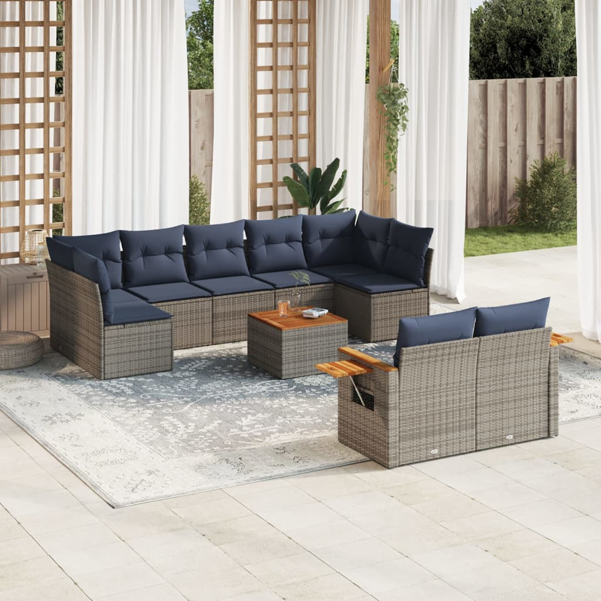 Ein Ecksofa im Freien mit blauen Kissen und einem kleinen Tisch auf einem Teppich. Vorhänge und Pflanzen im Hintergrund.