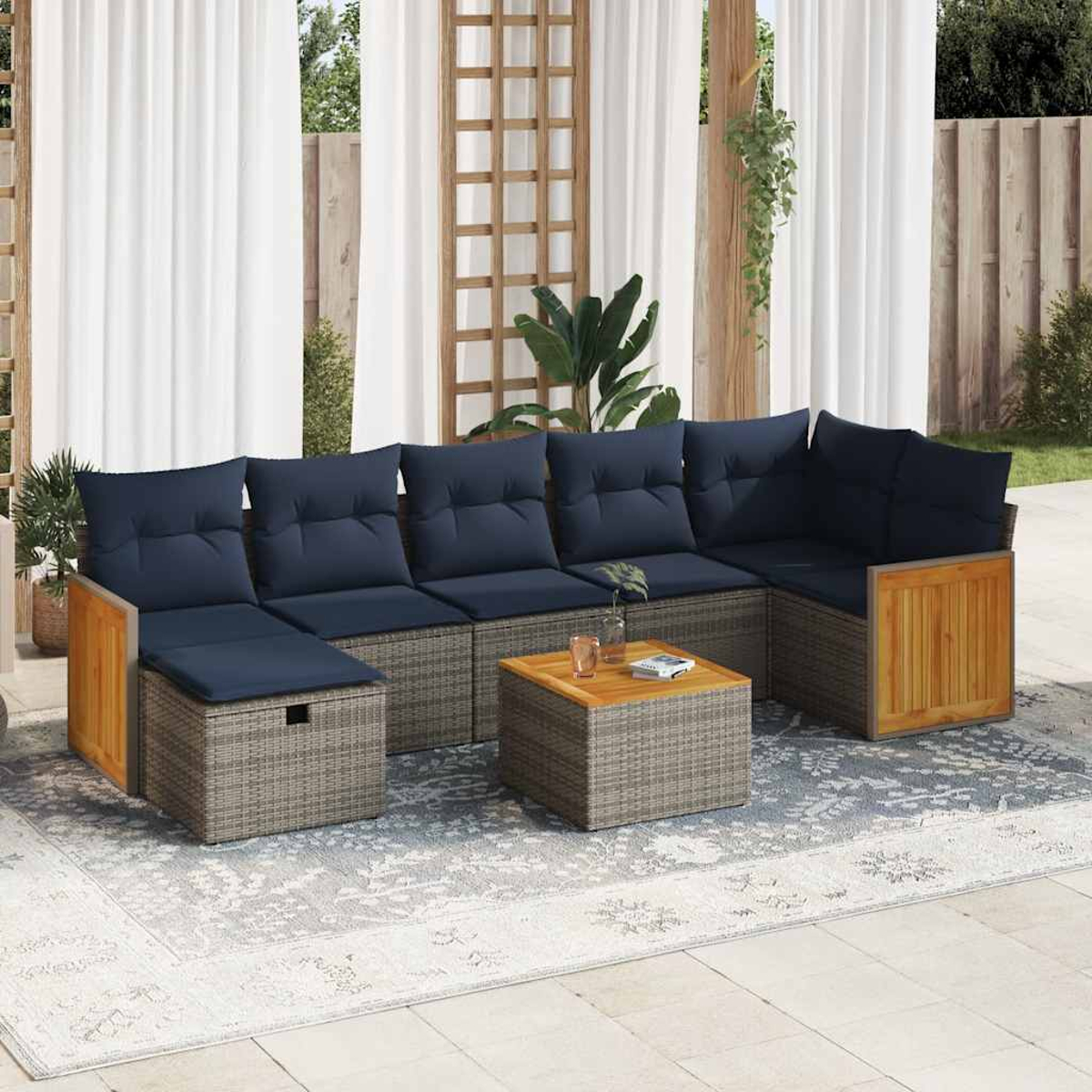 Ein Ecksofa im Freien mit blauen Kissen und einem kleinen Tisch auf einem Teppich. Vorhänge und Pflanzen im Hintergrund.