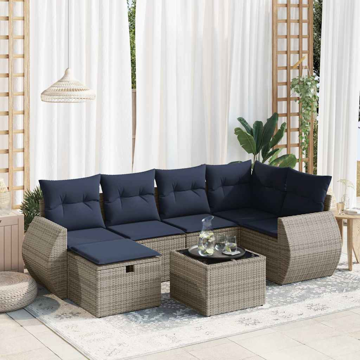 Ecksofa für den Außenbereich mit blauen Kissen und einem Couchtisch. Weiße Vorhänge im Hintergrund.