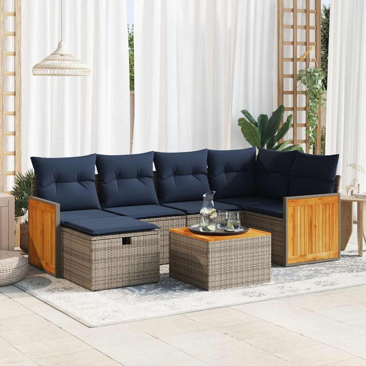 Graues Rattan-Ecksofa mit blauen Kissen und Holztisch auf einem Teppich, mit transparenten Vorhängen.