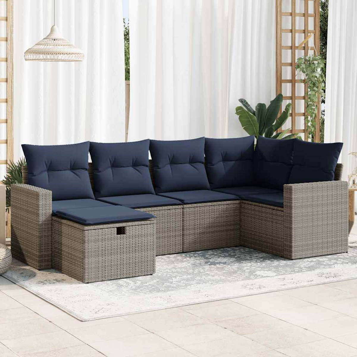 Ein graues Rattan-Ecksofa-Set mit marinefarbenen Kissen. Es beinhaltet einen Couchtisch und befindet sich auf einer Terrasse.