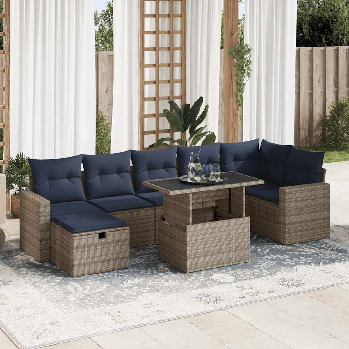 Gartenmöbel-Set mit grau gewebten Möbeln, marineblauen Kissen und einem Couchtisch mit Hubfunktion.