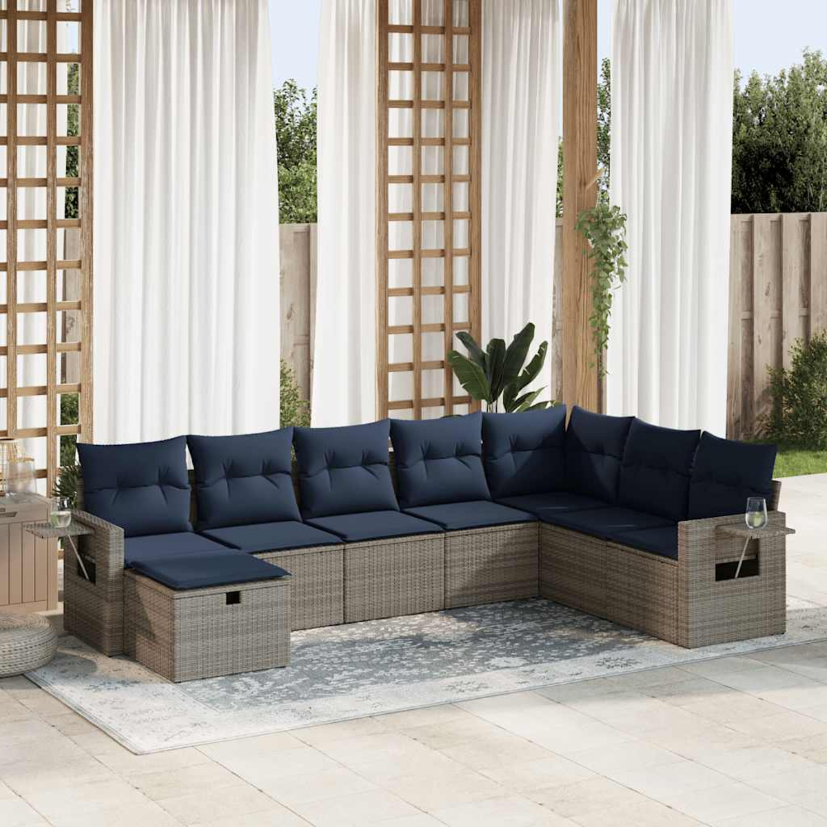 Graues Ecksofa aus Rattan mit marineblauen Kissen und passendem Couchtisch. Terrasse.
