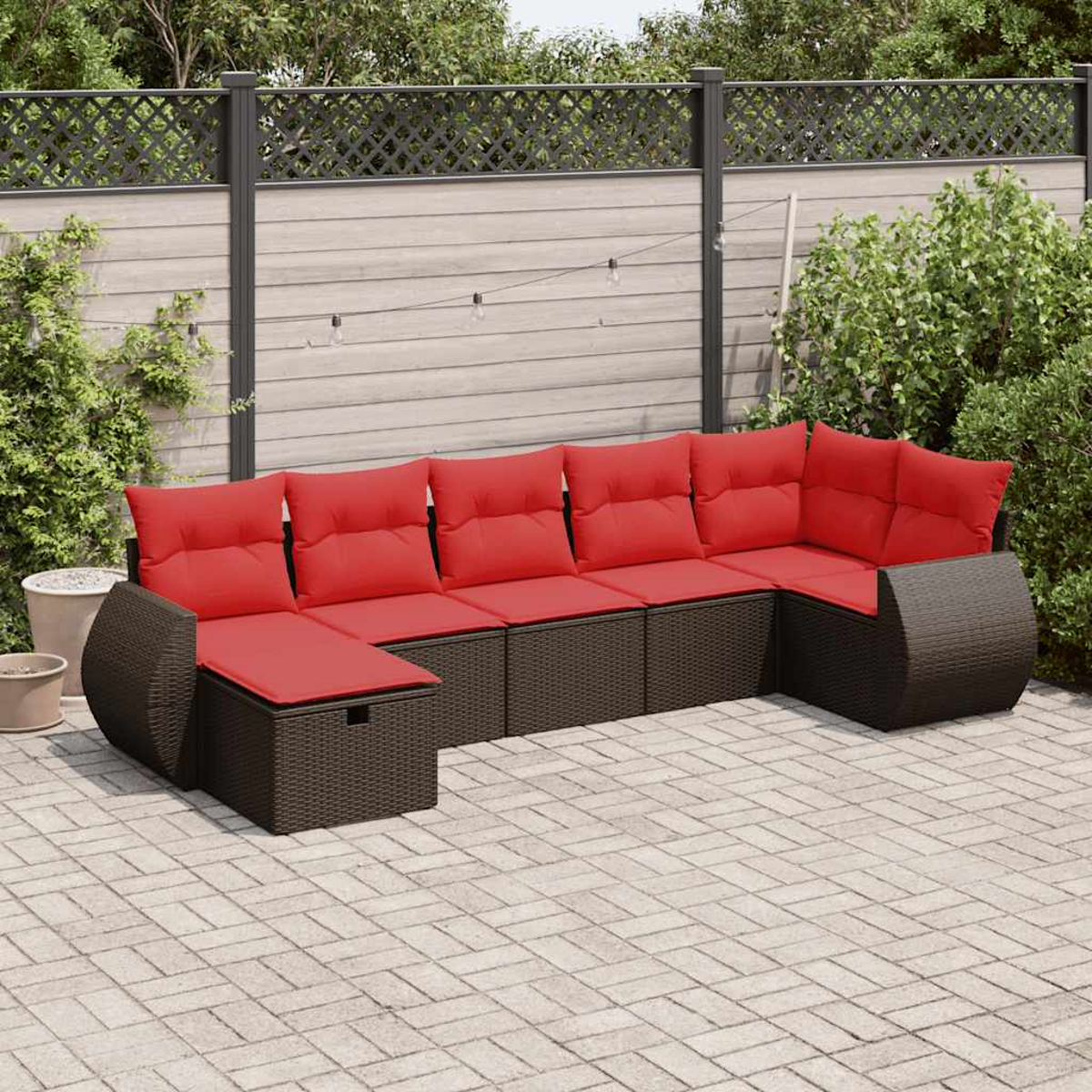 Un sofá seccional para exteriores con cojines rojos, en un jardín.
