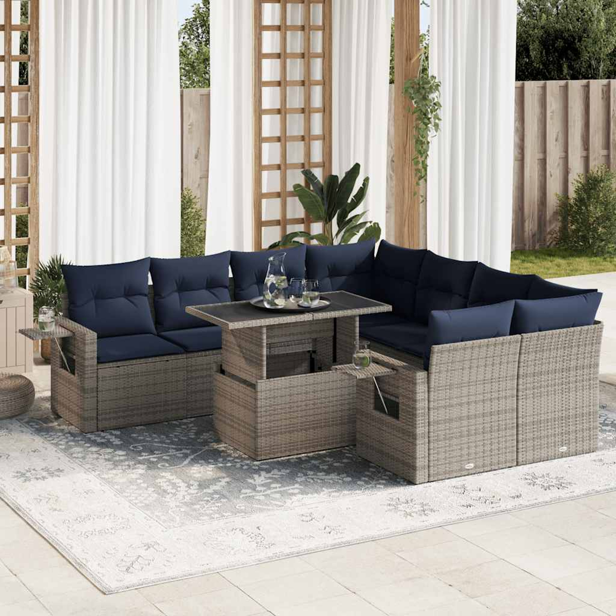 Ecksofa im Freien mit blauen Kissen und Tisch mit Hubfunktion. Weiße Vorhänge im Hintergrund.