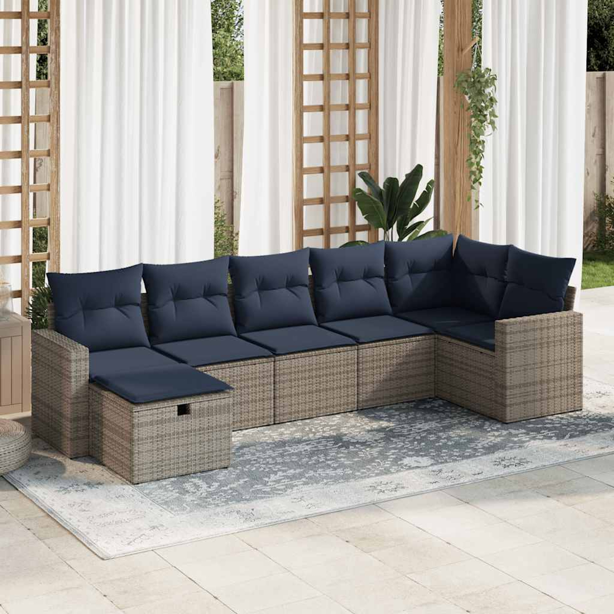 Ecksofa im Freien mit blauen Kissen, auf einem gemusterten Teppich angeordnet. Weiße Vorhänge im Hintergrund.