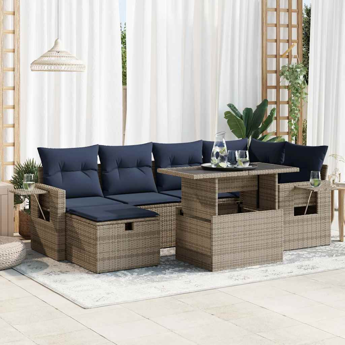 Ein Terrassenset mit einem Ecksofa, zwei Sesseln und einem Tisch. Blaue Kissen und ein Teppich sind sichtbar.