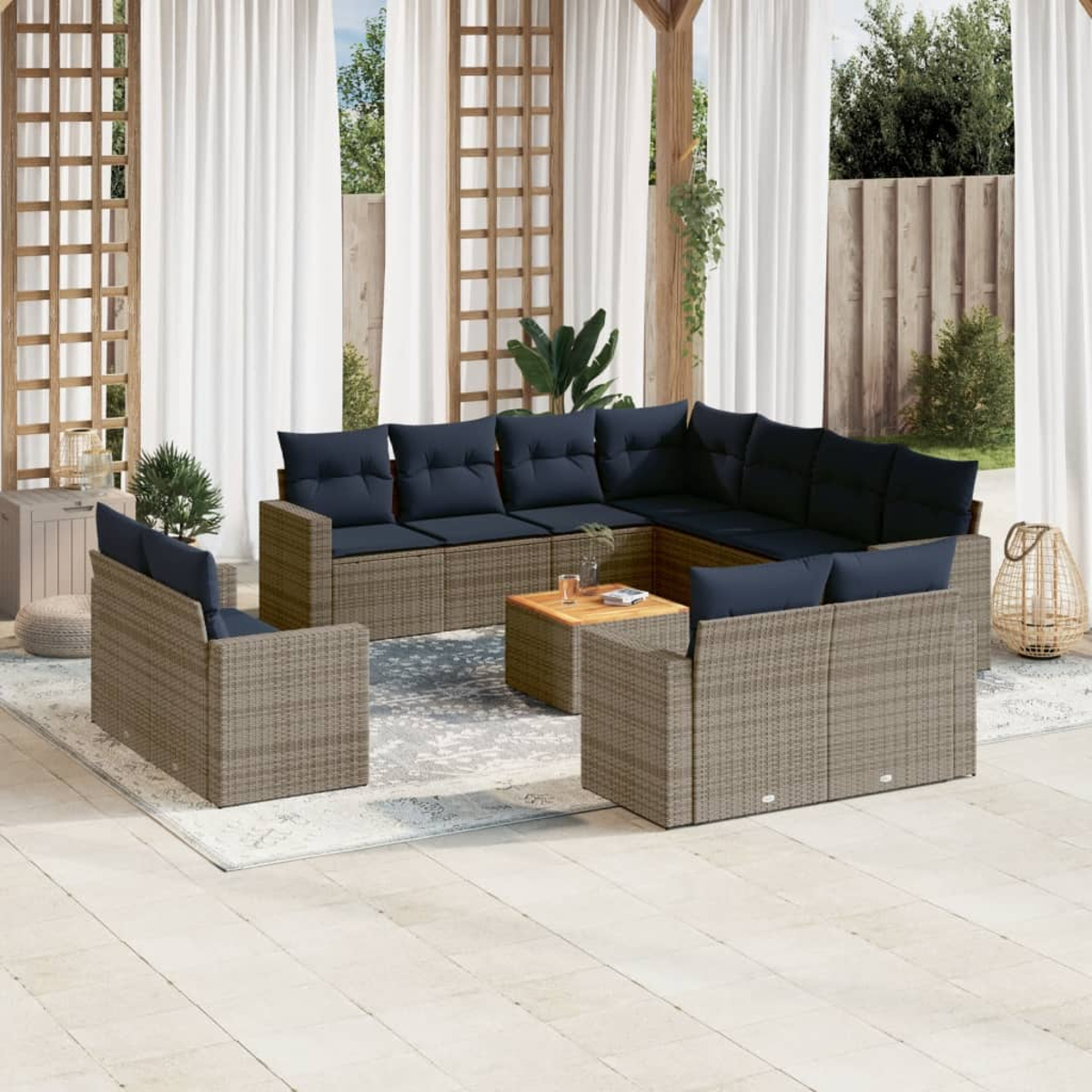 Ein Terrassen-Set mit einem großen Ecksofa, zwei Sesseln und einem Couchtisch. Alles aus Rattan mit blauen Kissen.
