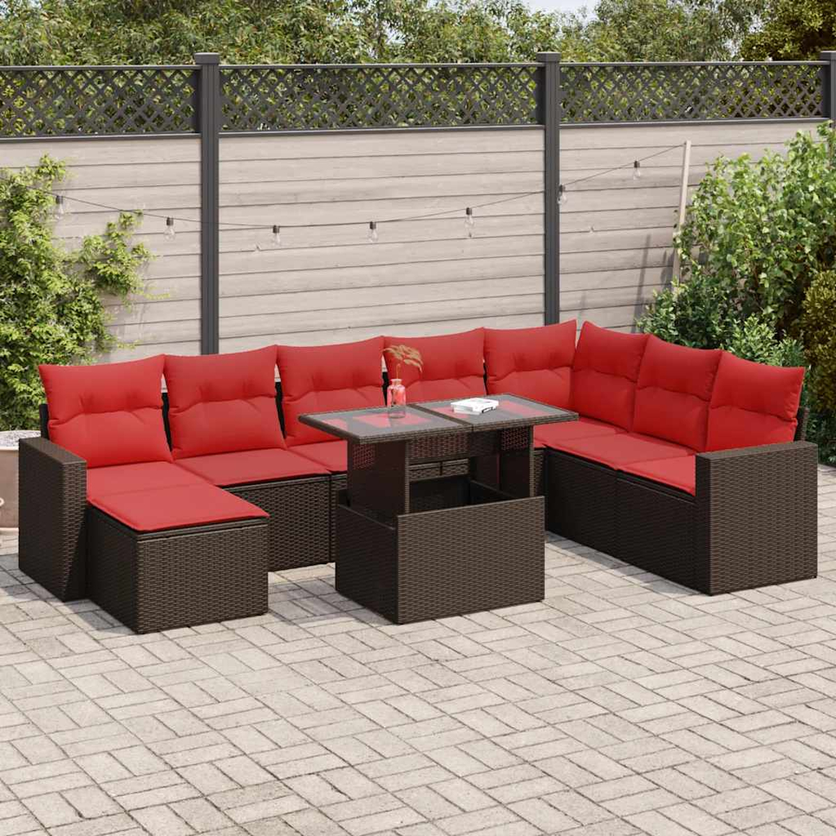 Braunes Korbmöbel-Set mit roten Kissen und einem Tisch mit Glasplatte im Freien.