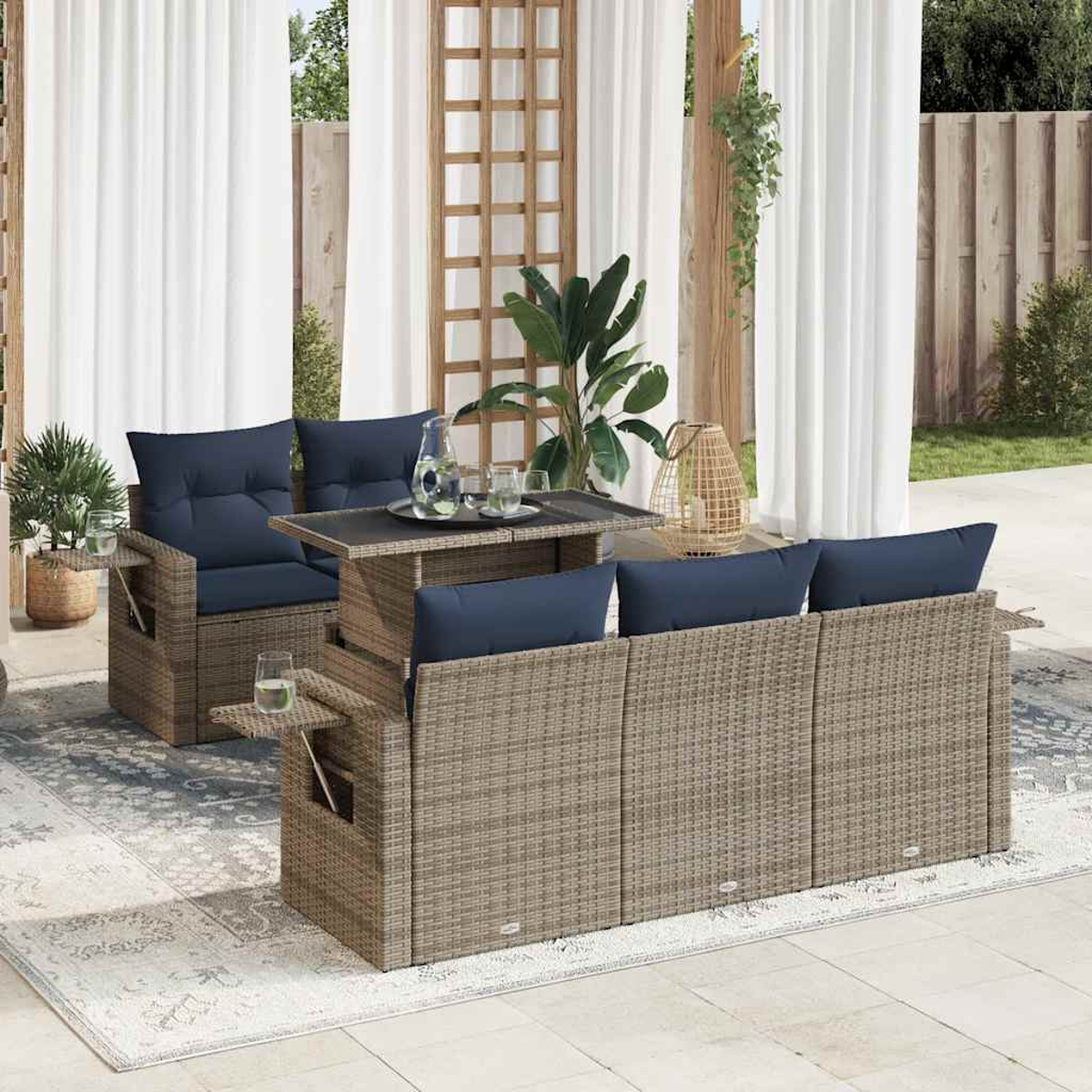 Gartenmöbel-Set aus Rattan mit Tisch und Sofa mit blauen Kissen. Weitere Teile und Dekoration in der Szene.