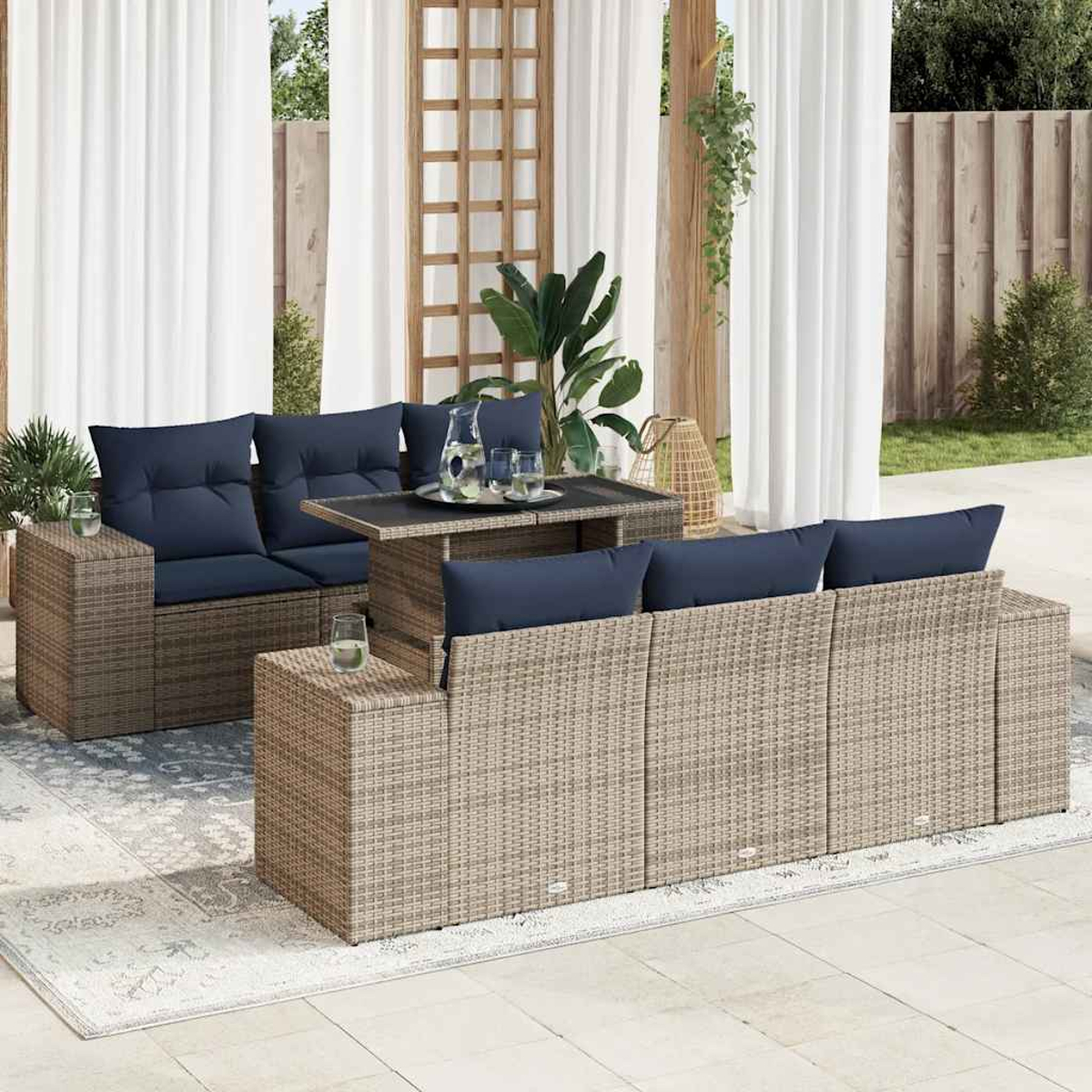 Terrassenset mit grauen Geflechtmöbeln und blauen Kissen. Mit einem Tisch mit Hubfunktion.