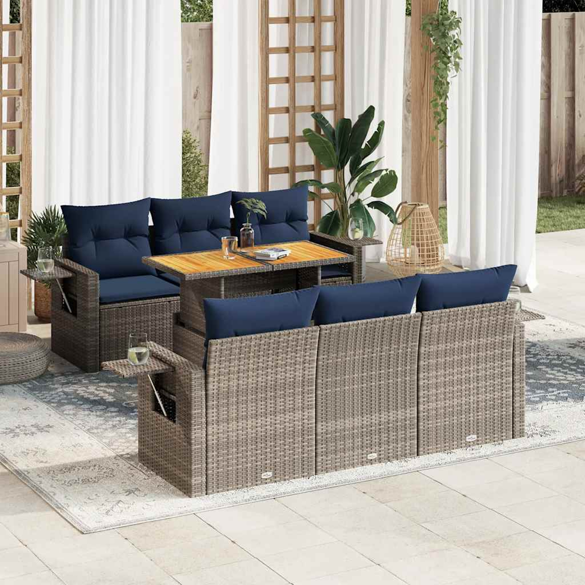 Outdoor-Sitzbereich mit Flechtmöbeln, marineblauen Kissen, Tisch mit Getränken und gemustertem Teppich.
